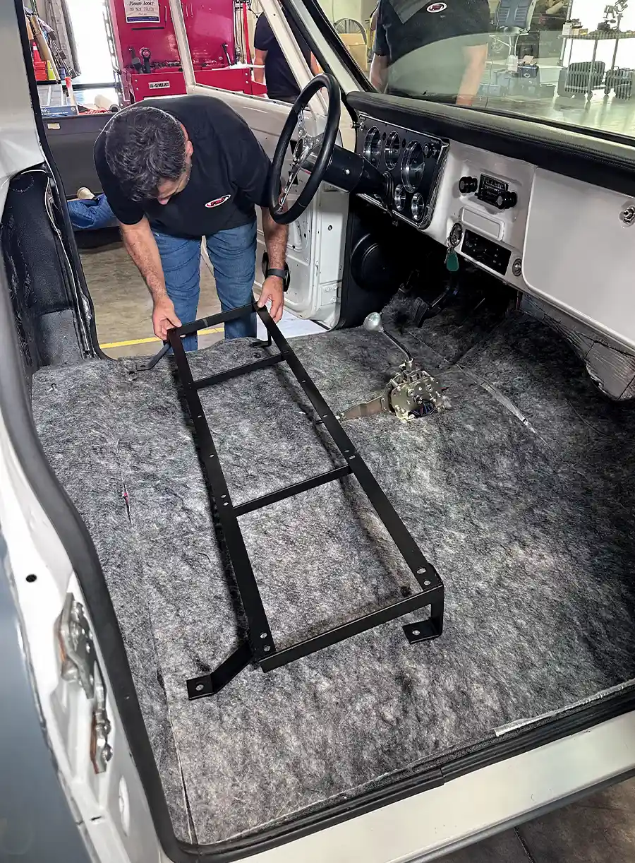 Technician positioning seat bracket inside truck’s insulated cab