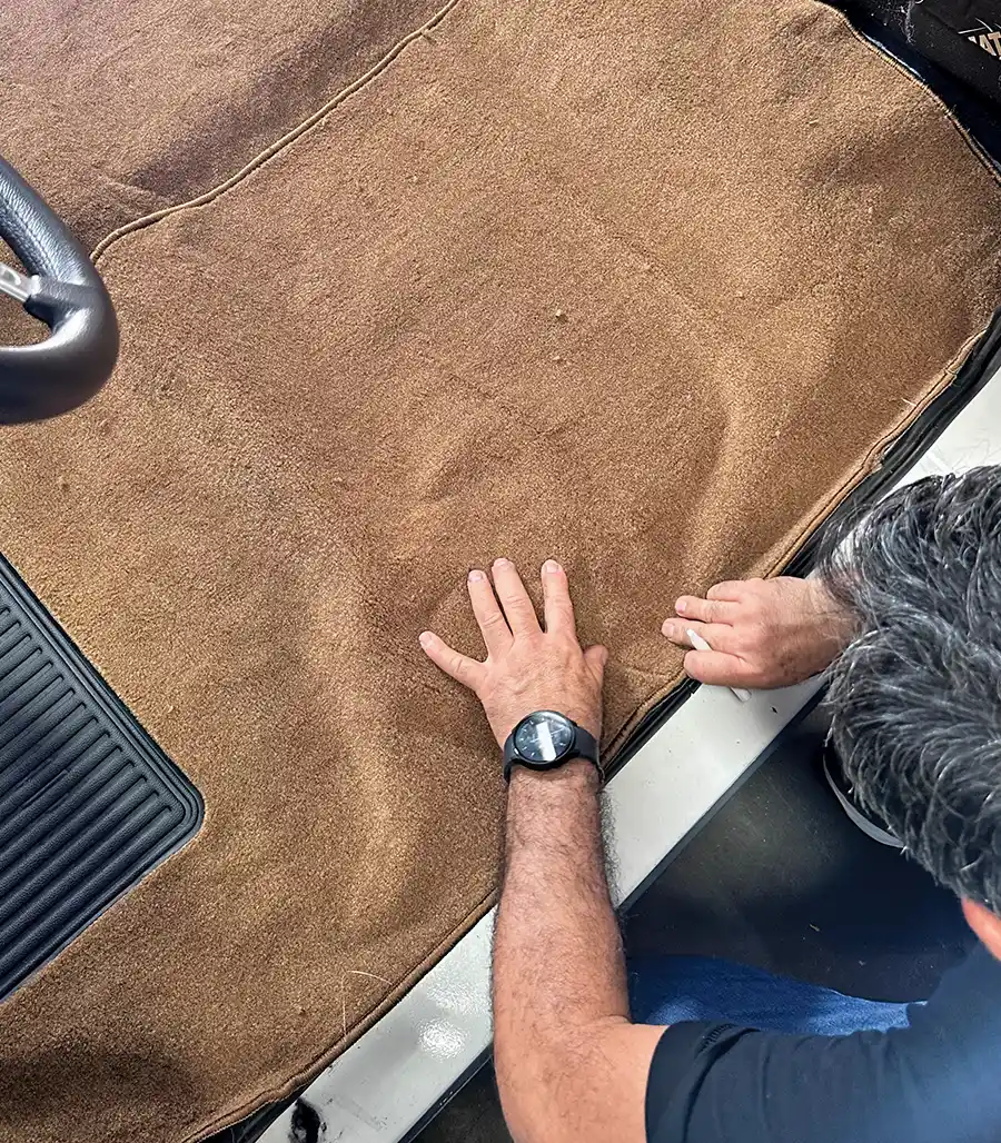 Black kick panel being adjusted beneath dashboard over new carpet