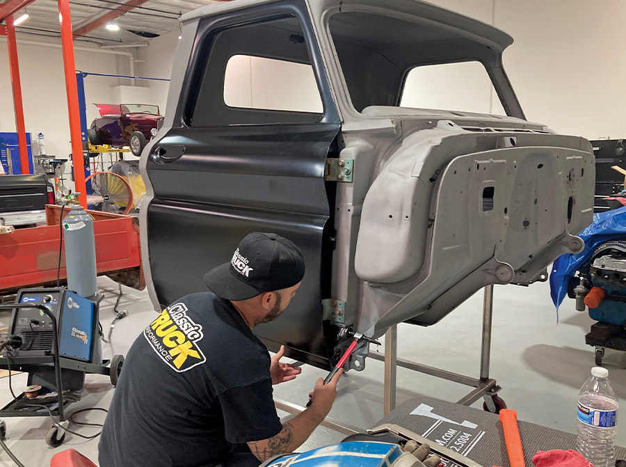 Classic truck cab undergoing rocker panel replacement in a restoration shop