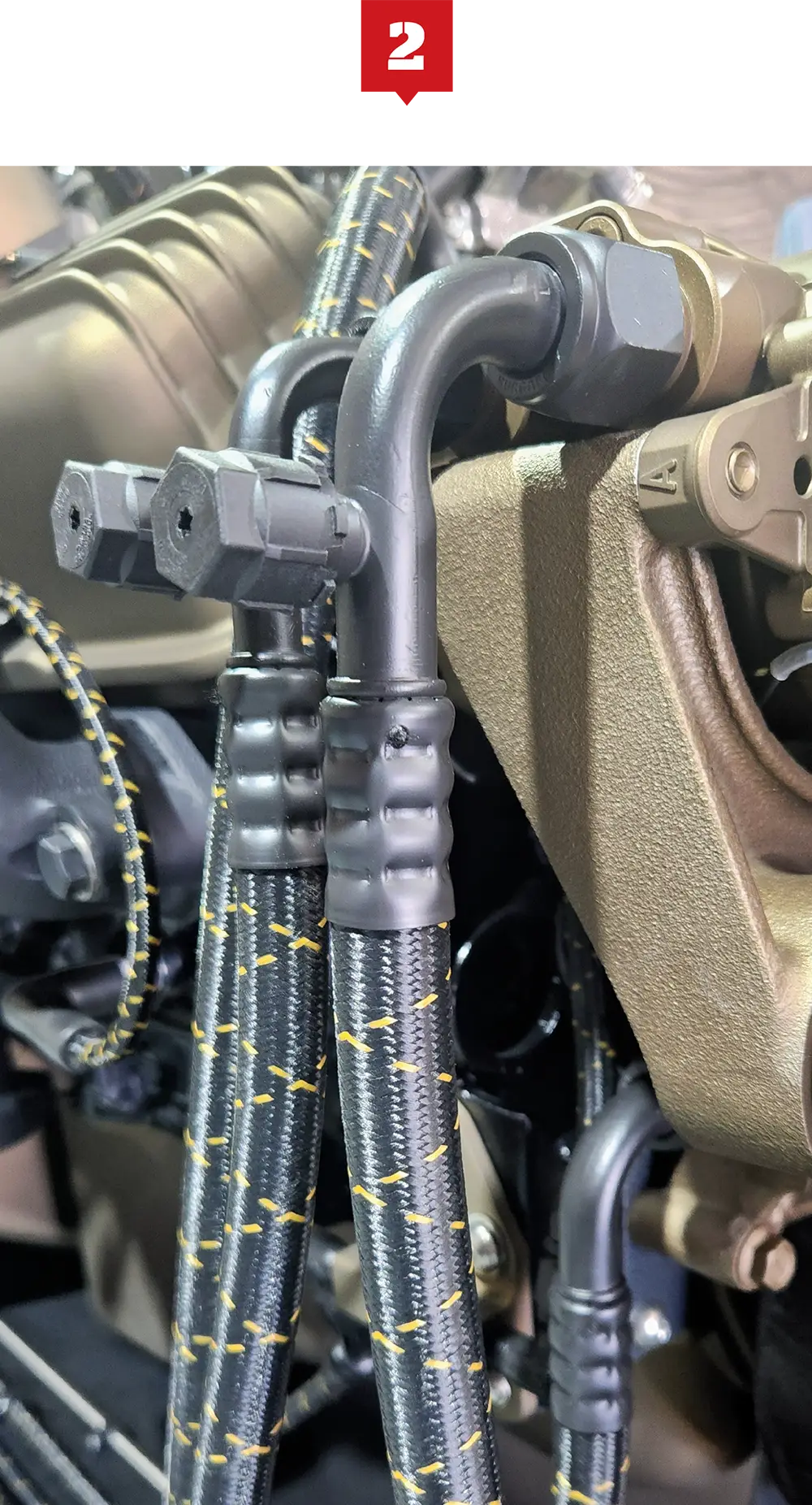 Close-up of braided hoses connected to metallic fittings on machinery.
