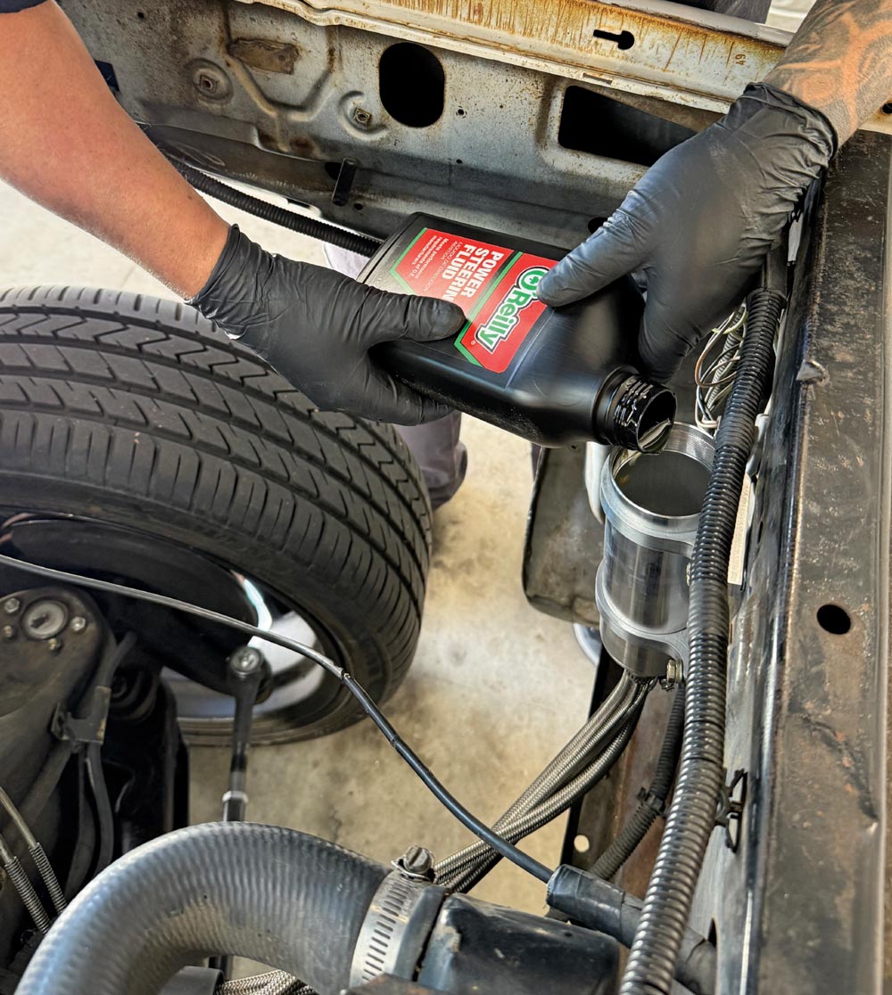 O’Reilly power steering fluid being poured into the remote reservoir during fill and bleed process