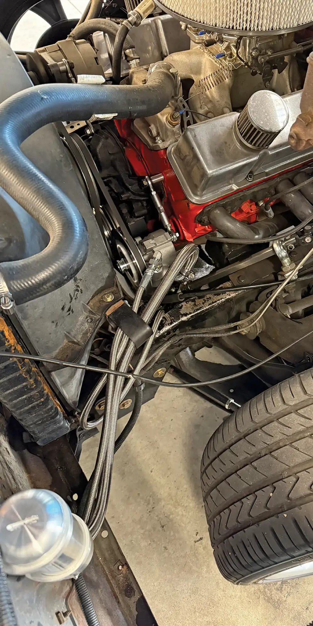Full engine bay view showing braided hose routing to Borgeson-style power steering conversion on small-block