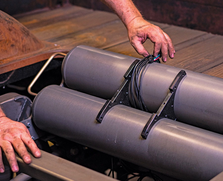 Routing wiring harness over AccuAir tank mounts inside wood-lined bed