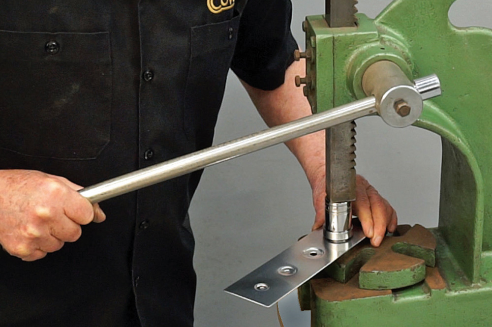 close-up of the arbor press setup with dimple dies and a sample panel