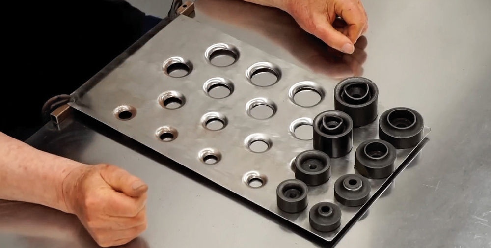 large sheet of aluminum with multiple formed dimples and corresponding dimple dies