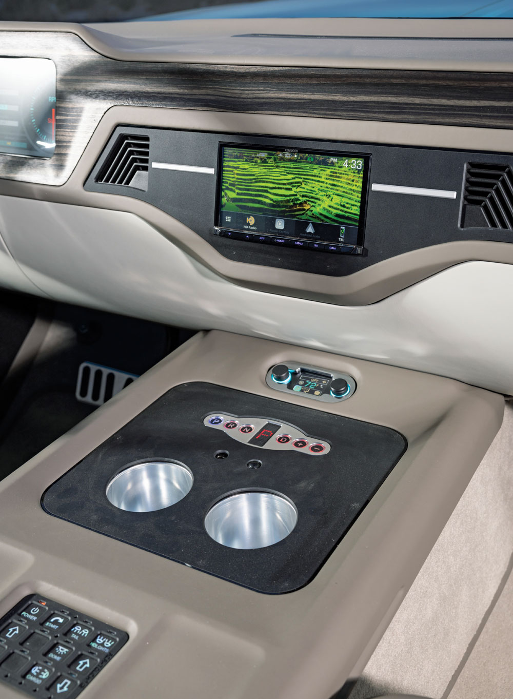 Interior dashboard and center console of a modern vehicle with a touchscreen, cup holders, and control features.