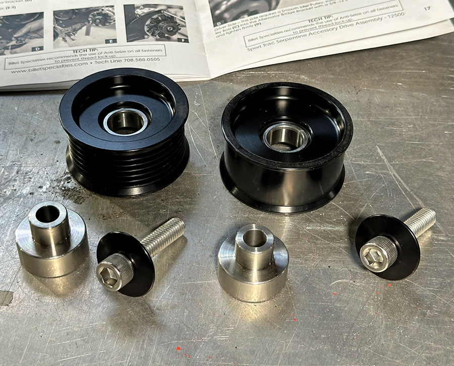 Smooth and grooved idler pulleys with spacers laid out next to Billet instructions