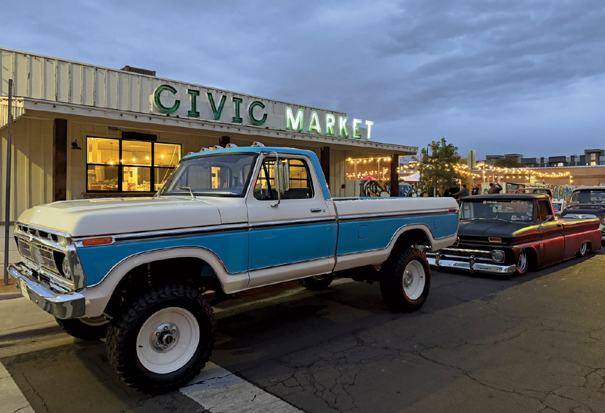 Lifted 1973–1977 Ford F-250 4x4 parked beside slammed 1960–1966 C10 under string lights