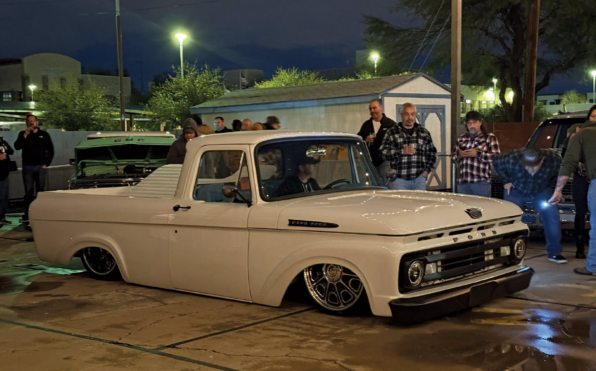Bagged 1961–1966 Ford F-100 Unibody lays frame under show lights with crowd gathered