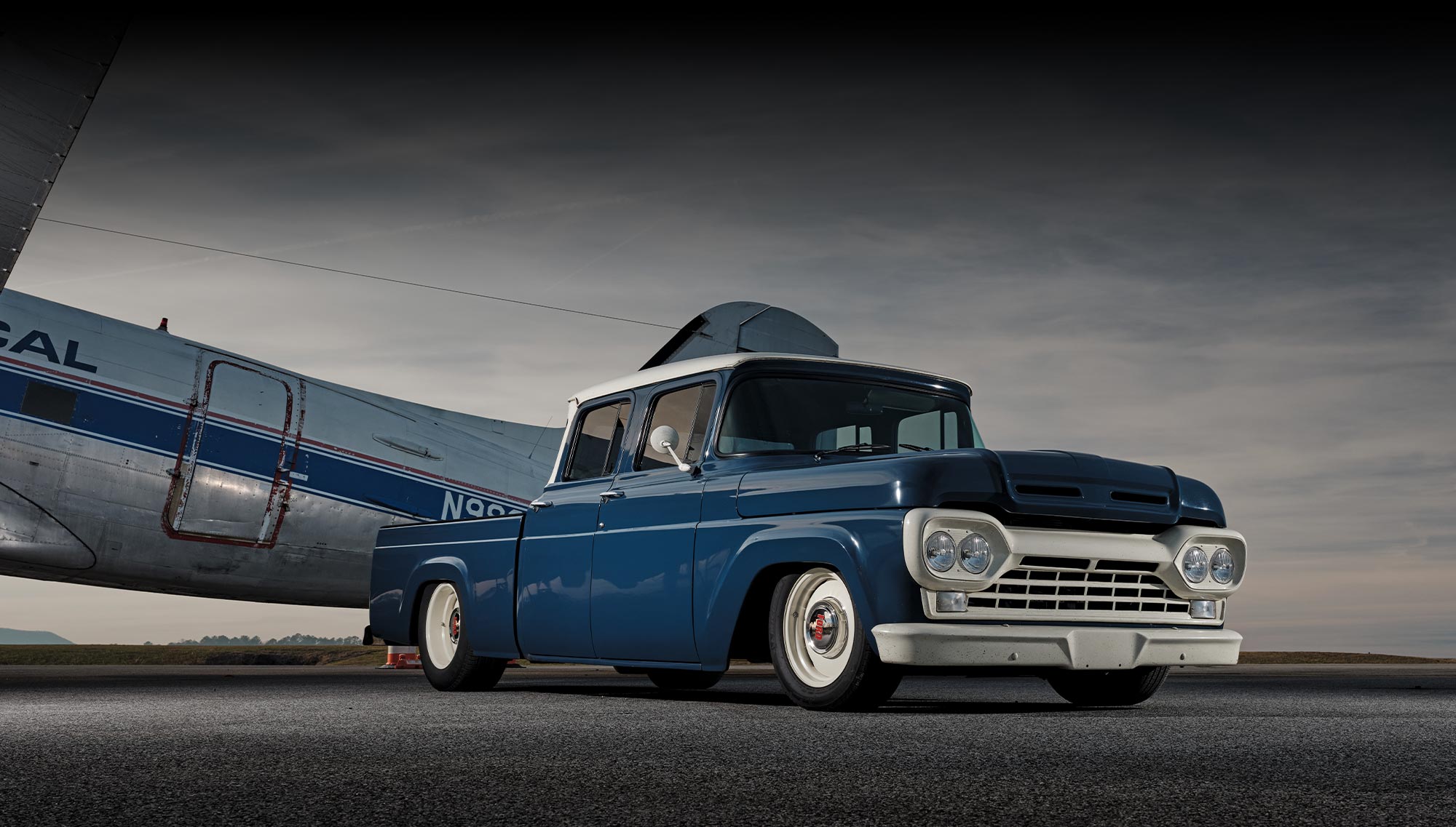 1960 Ford crew cab truck custom build whitewall tires parked under aircraft wing