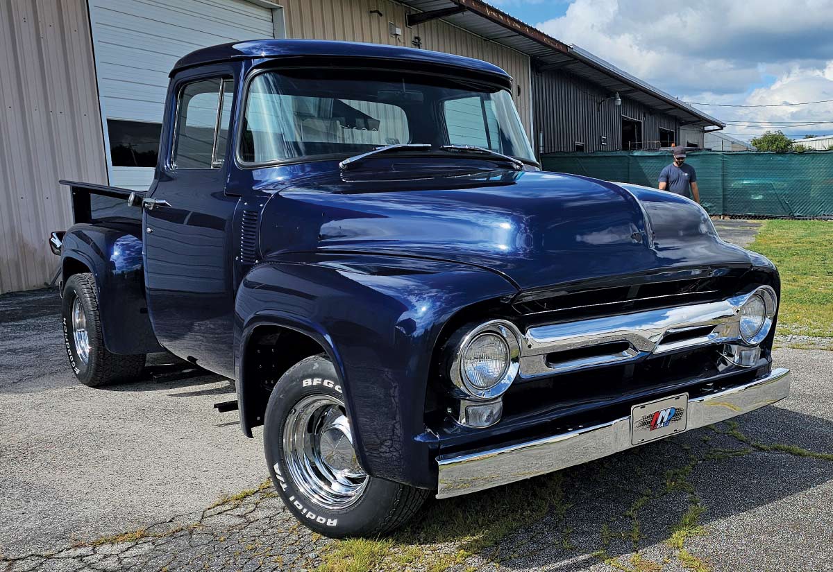 A close-up, low-angle shot of a classic dark blue Ford F-100 pickup truck.