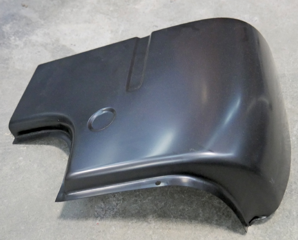 A medium, slightly elevated shot of a new, unpainted, black metal rear cab corner patch panel for a classic Ford F-100 truck.