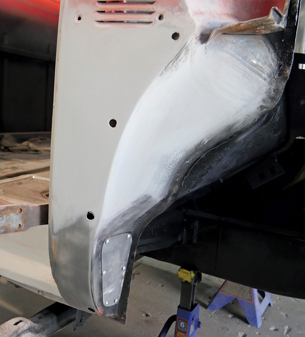 A close-up side view of the repaired front cab corner of a red classic pickup truck. 