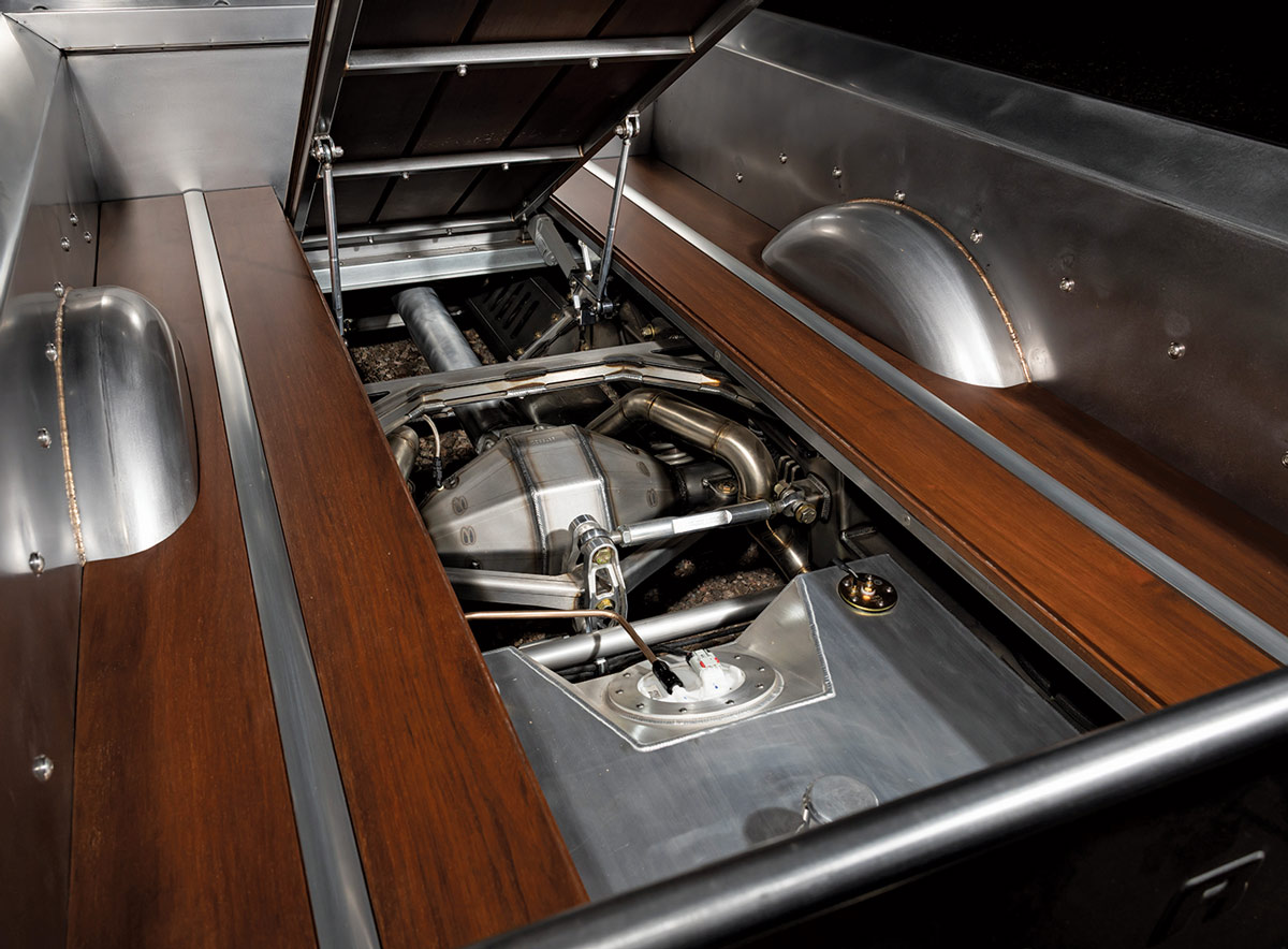 A close-up of the custom truck bed of a classic pickup truck. The bed has a dark wood floor with polished metal strips.
