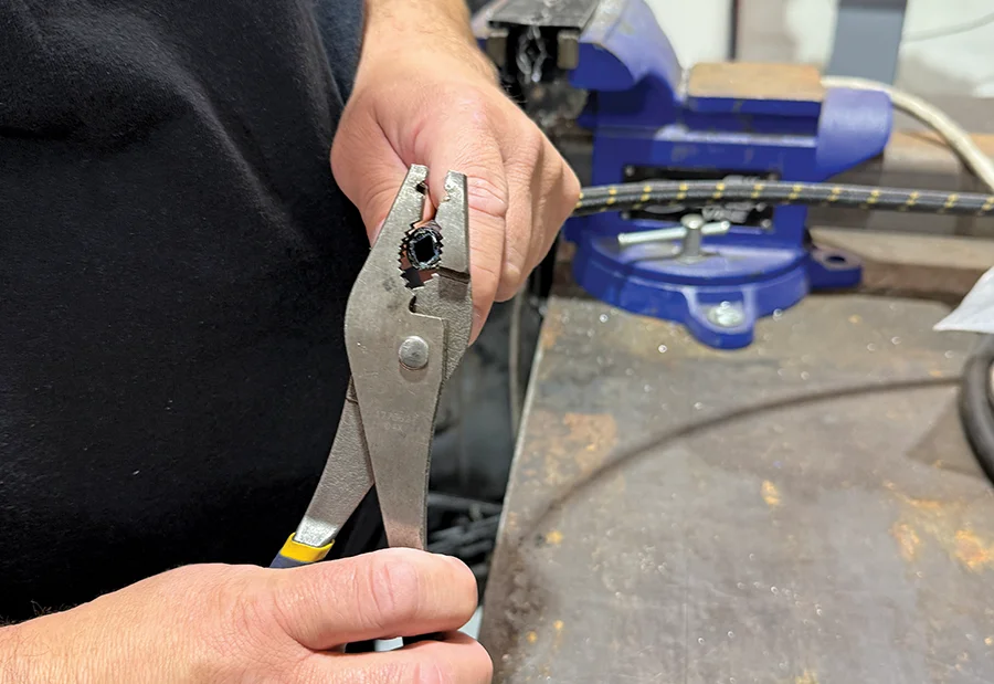 Inspecting braided hose cut with pliers to verify clean straight end for fitting
