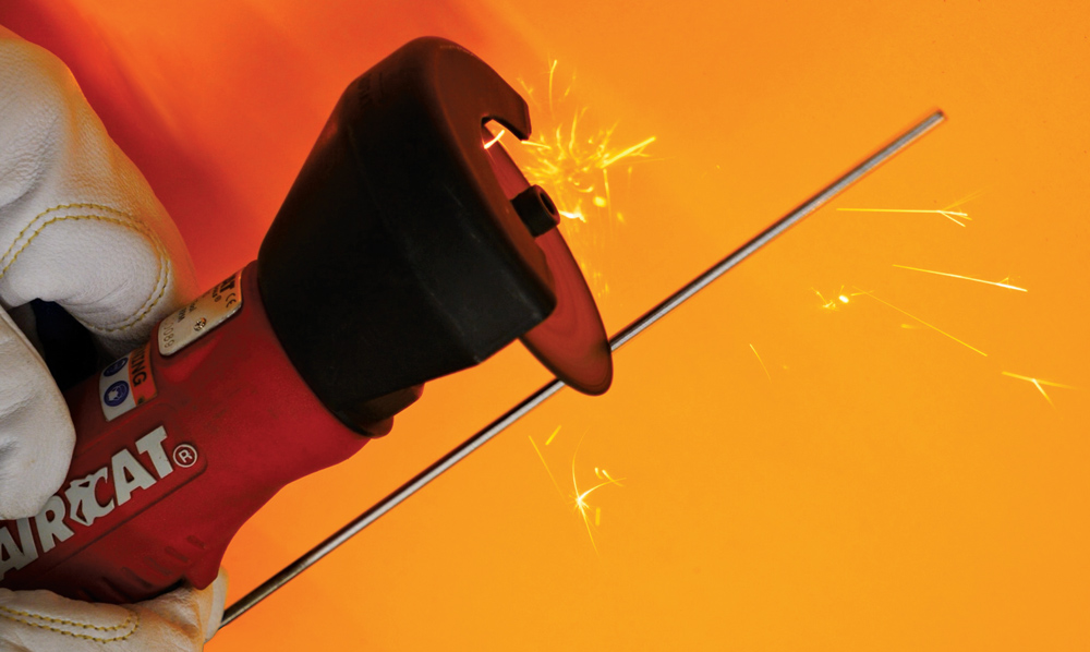 AIRCAT red rotary tool cutting tungsten, gloved hand, bright sparks, orange backdrop