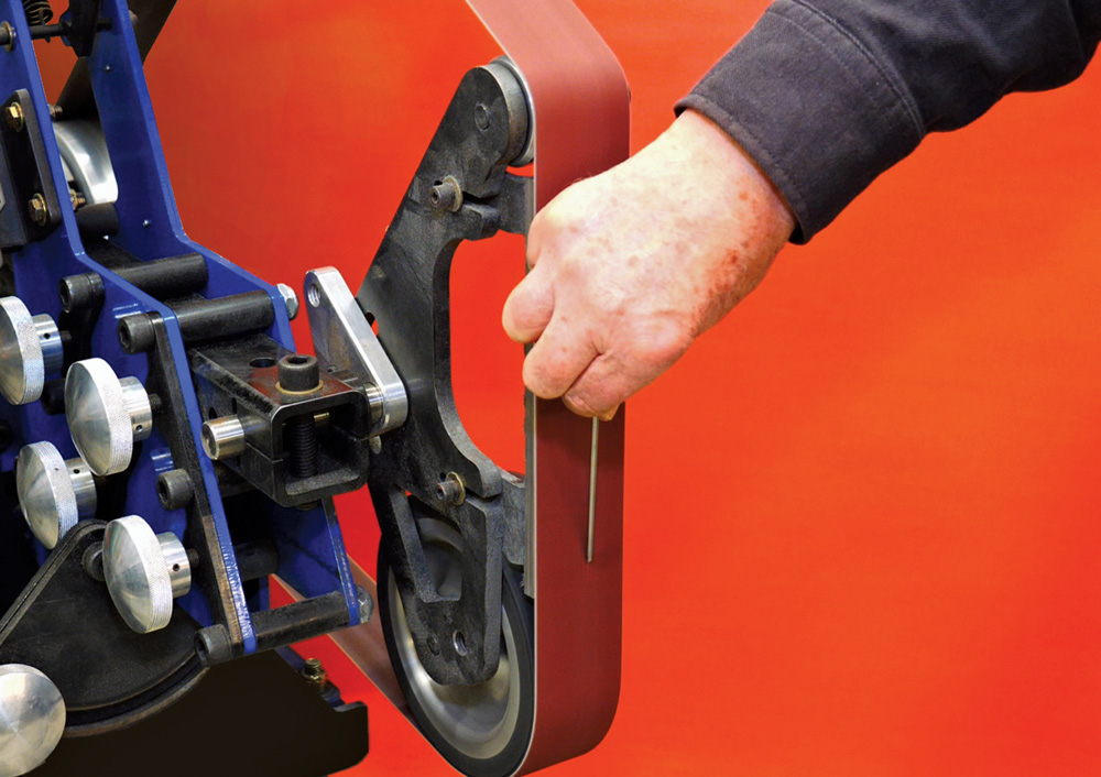 Belt grinder sharpening tungsten, blue machine, maroon belt, controlled taper grind