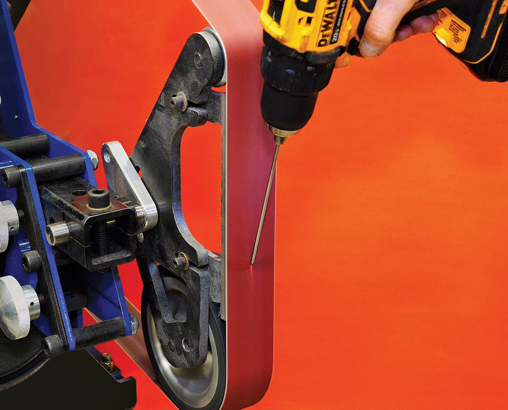 DeWalt cordless drill spinning tungsten on belt grinder, hands-on sharpening setup