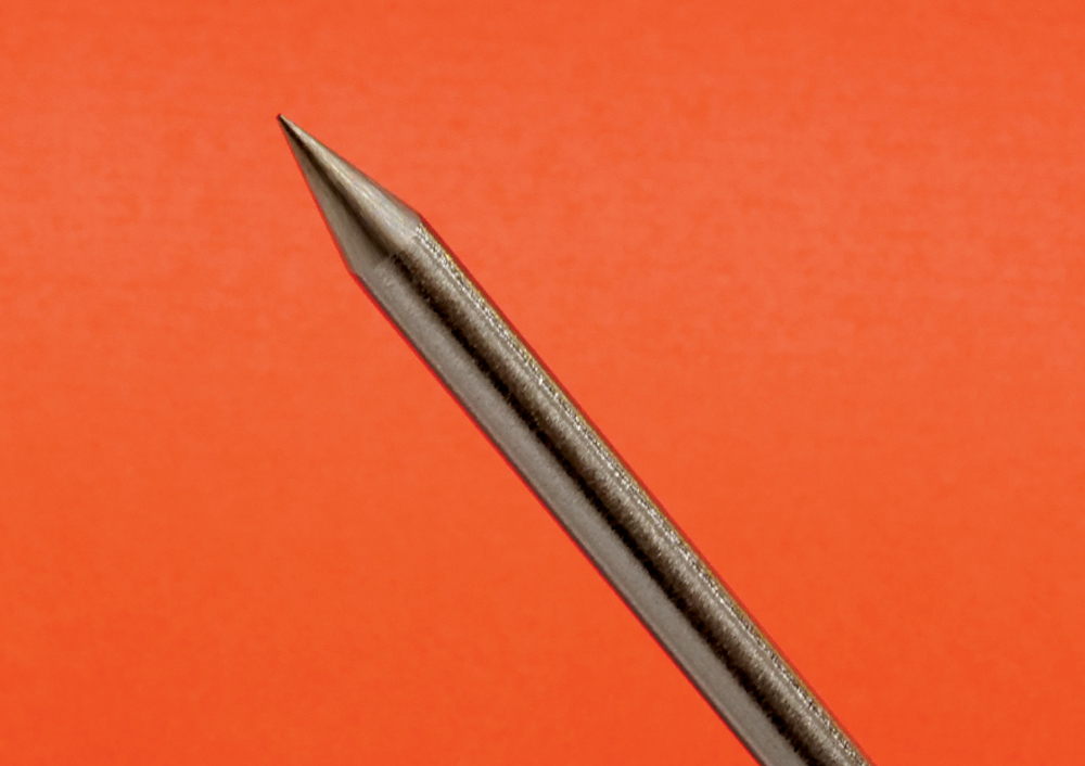 Single TIG tungsten electrode, near-horizontal orientation, clean grind, orange background
