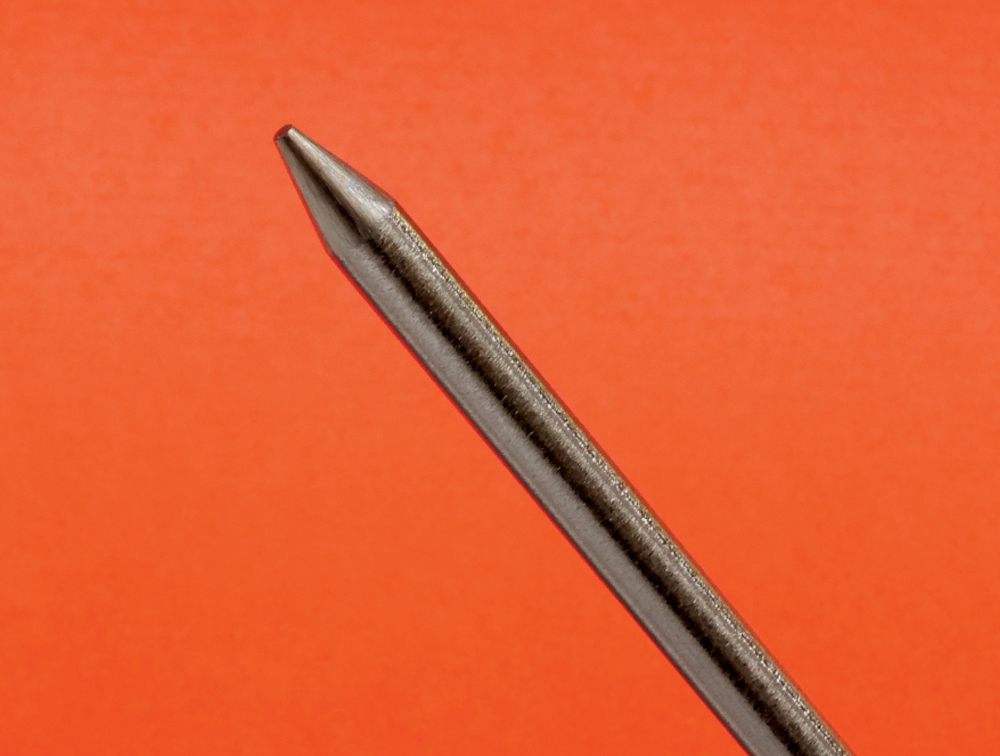 TIG torch with pink MILLER #5 cup, tungsten protruding, white collar visible, orange background