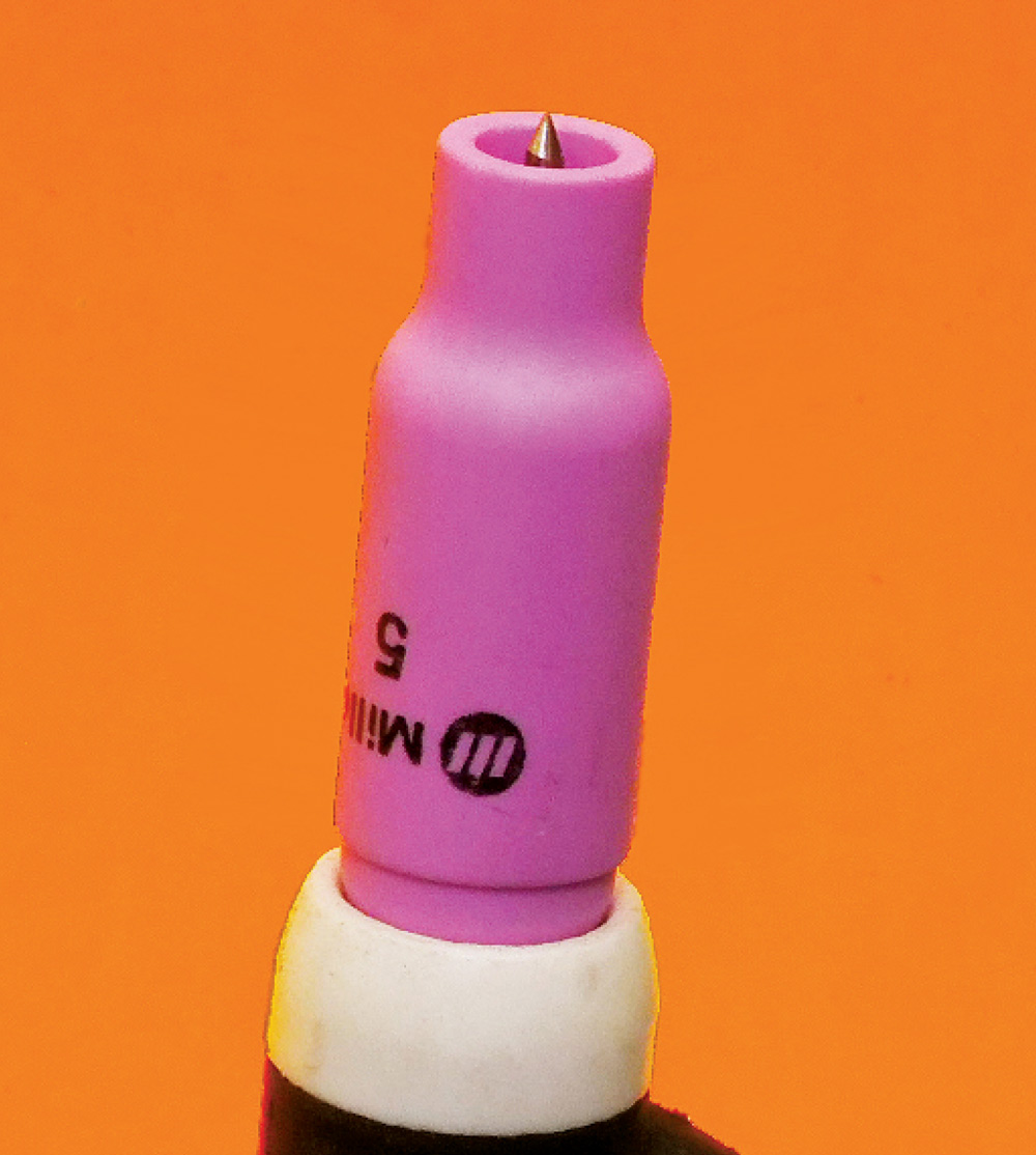 TIG torch, pink MILLER #5 cup, centered tungsten, partial logo text visible, orange background