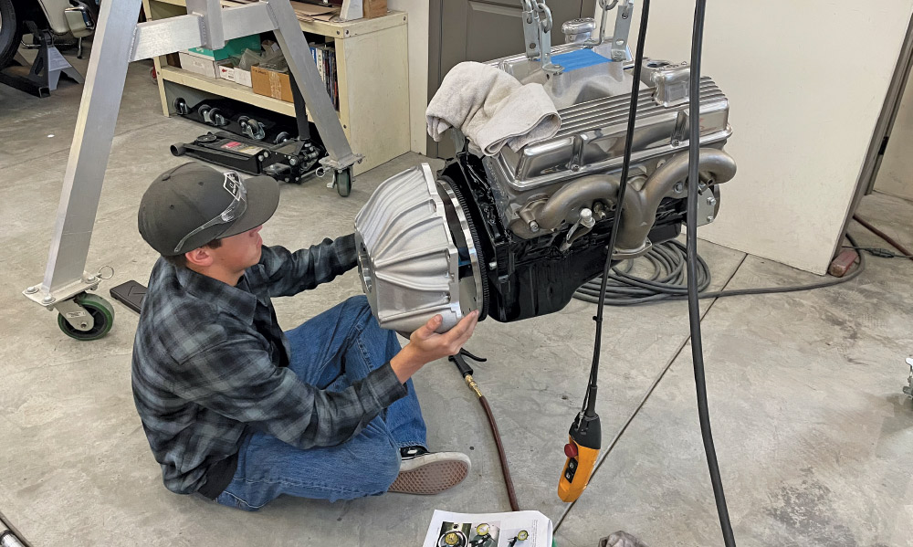 installing engine bellhousing assembly, chain hoist positioning, plaid shirt worker