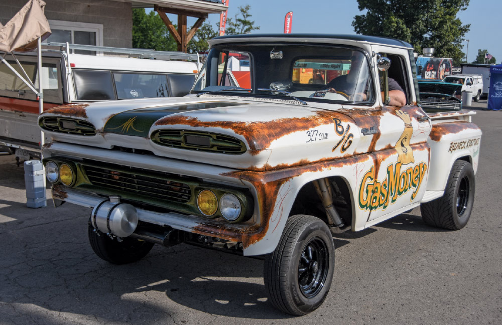 A custom, high-riding Chevrolet C10 pickup truck with a faux-patina rust finish, aggressive tires, and "Gas Money" painted on the side.