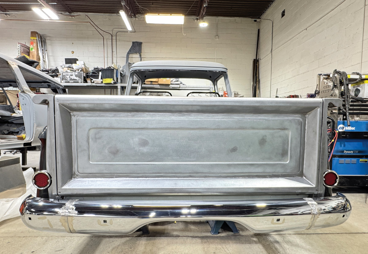 Chevy Task Force tailgate, bare metal, installed on truck, chrome bumper taped, red taillights, shop with Miller Dynasty 350