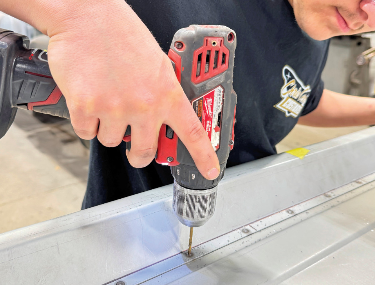 Drilling spot welds, red Milwaukee drill, tailgate reinforcing strip, safety glasses and ear protection, Club Carce Customs shirt