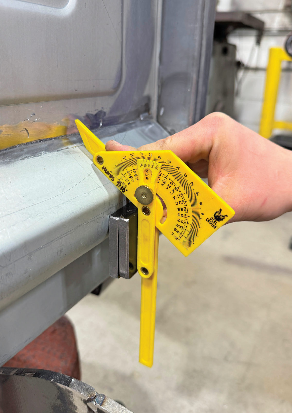 Yellow Empire angle finder on tailgate corner, degree scale visible, welded joint
