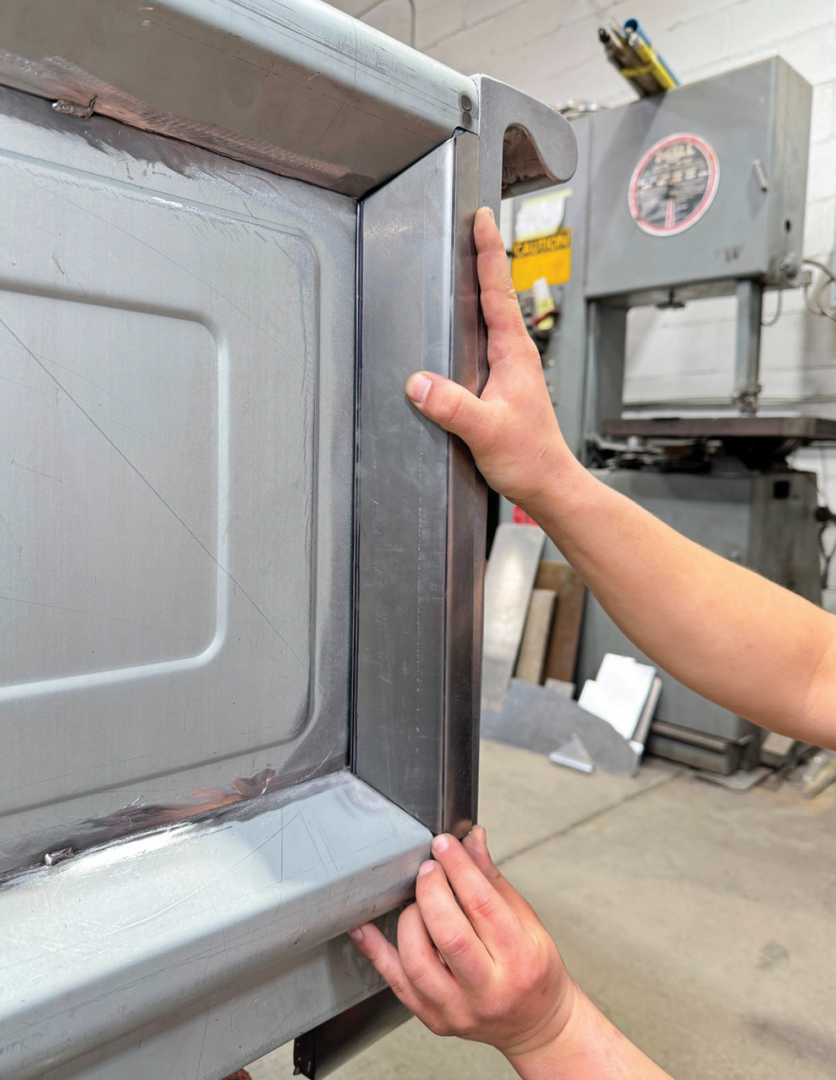 Test-fitting inner edge panel on tailgate, hand alignment, clean silver metal