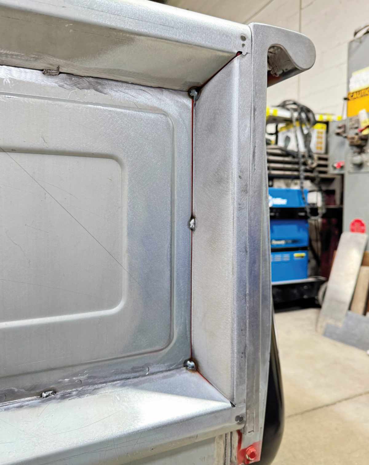 Finished inner corner panel, welds blended smooth, minor grind marks, Miller machine in background