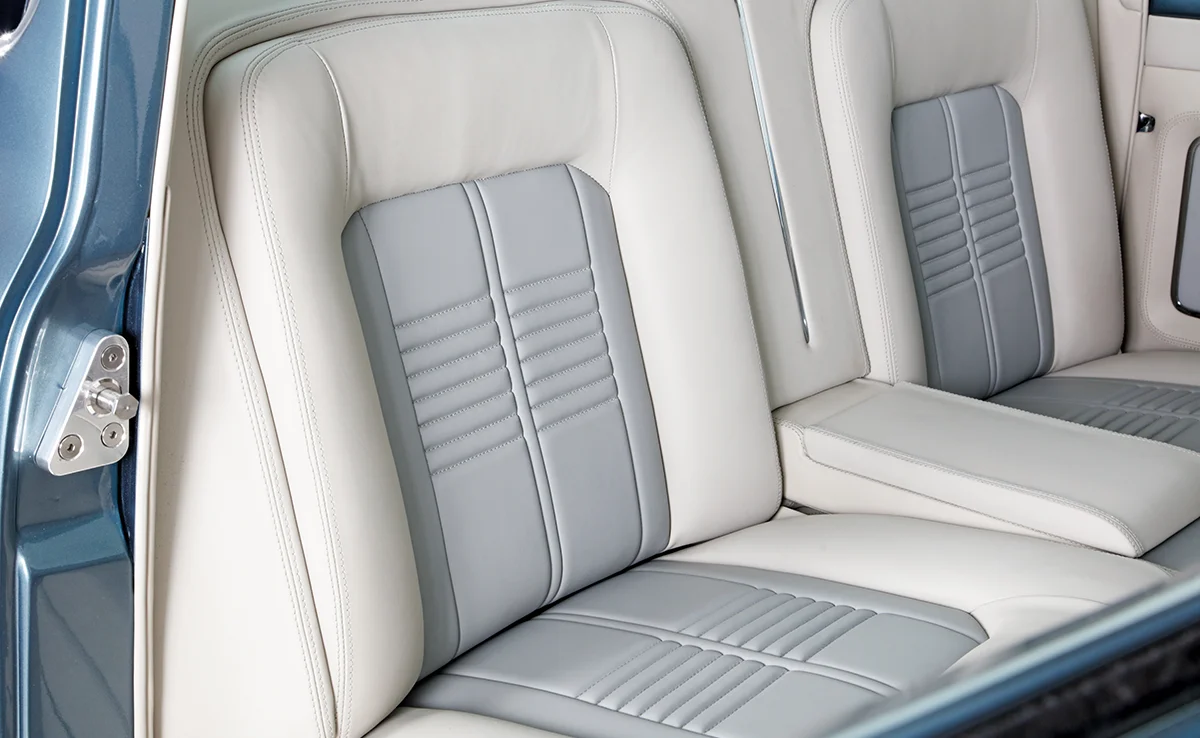 Custom interior upholstery of a vintage truck, featuring two-tone cream and gray leather seats with detailed horizontal stitching and modern design.