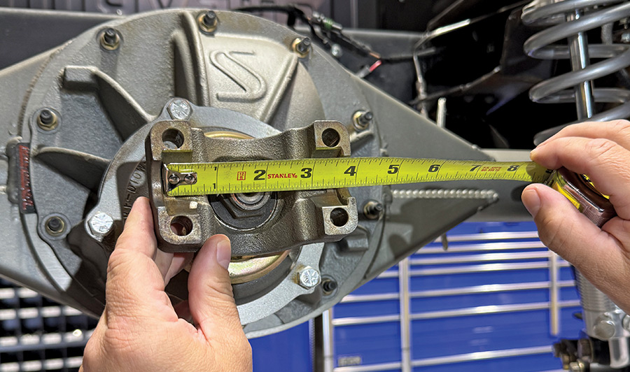 Technician accurately measuring the flange width of a high-performance rear axle yoke with a Stanley tape measure, critical for selecting the correct U-joint size.