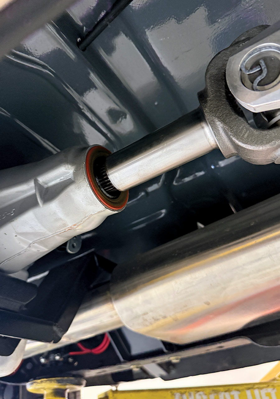 Close-up of a new driveshaft yoke being slid into the tail shaft of a transmission, showing the oil seal and splines during installation.