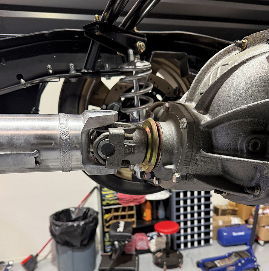 Close-up of a newly installed propeller shaft connecting to the rear end of a truck, showing the U-joint caps and differential cover.