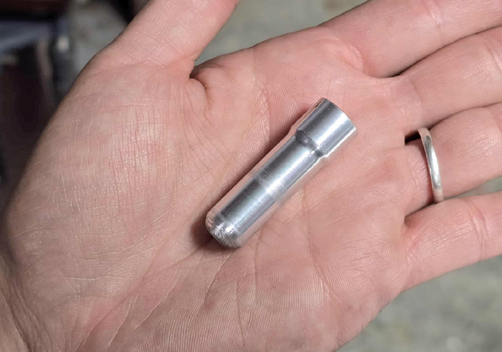 A palm holds a small, silver cylindrical metal pin with a rounded tip.