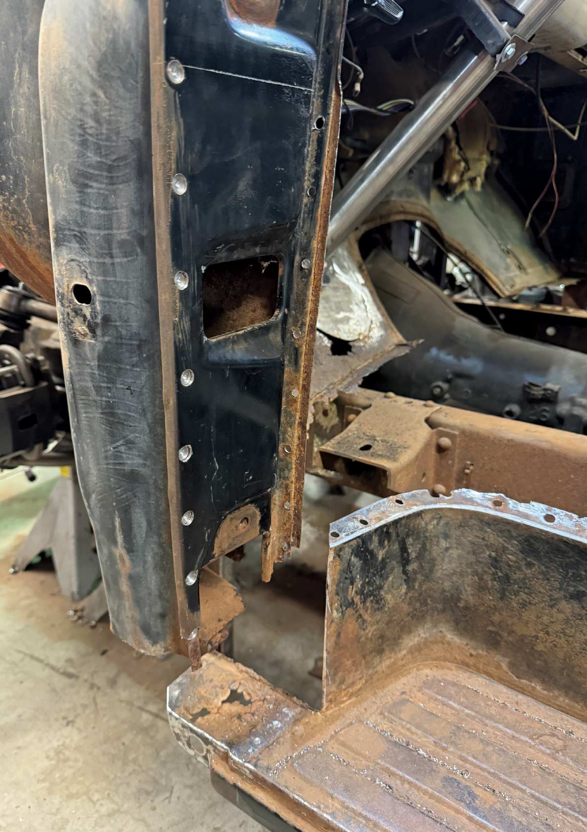 Close-up of a truck door pillar where old rusted metal has been cut out to make room for new replacement panels.