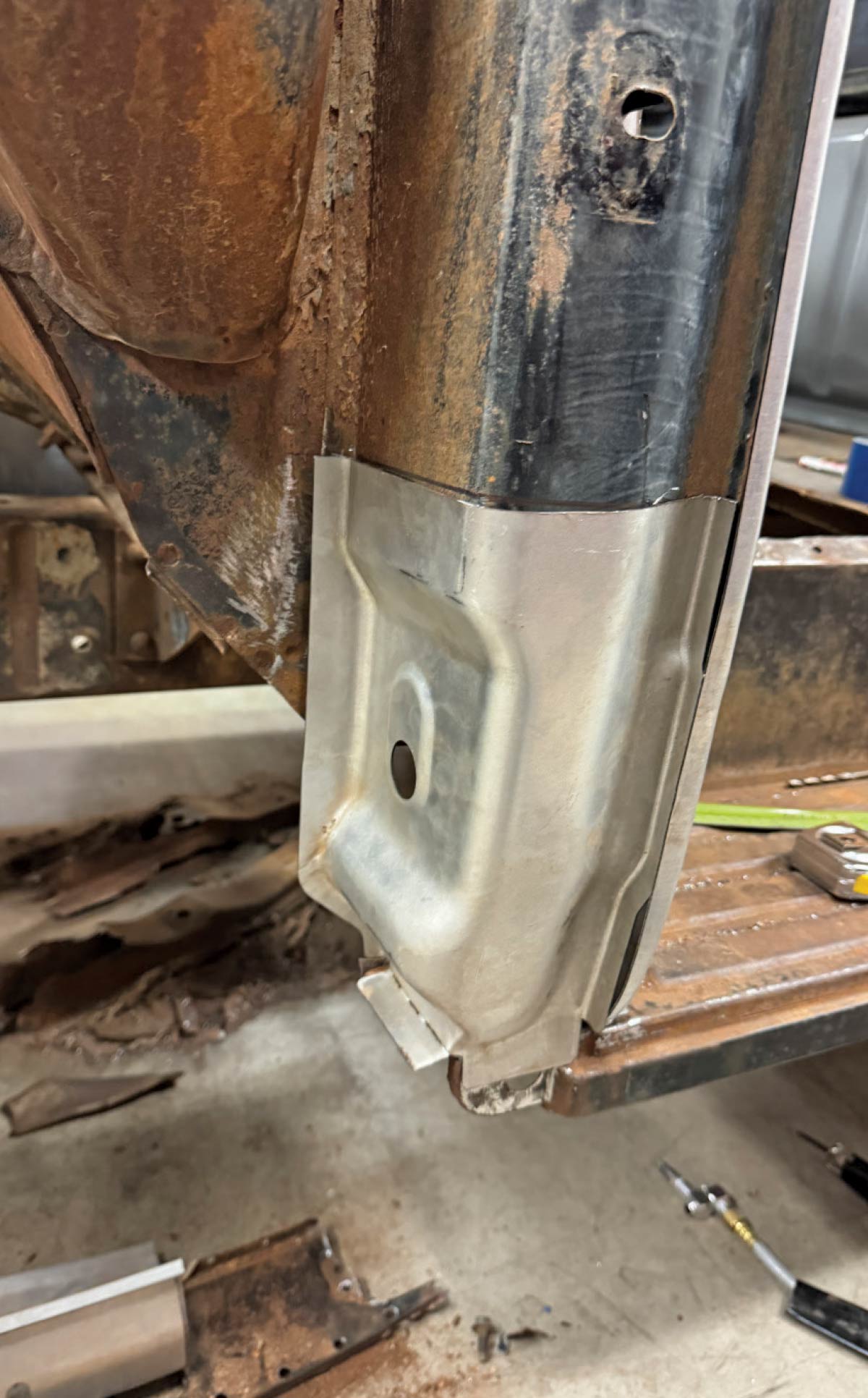 A new steel "front of cowl" repair panel is test-fitted over a rusted section of a vintage Ford truck cab.
