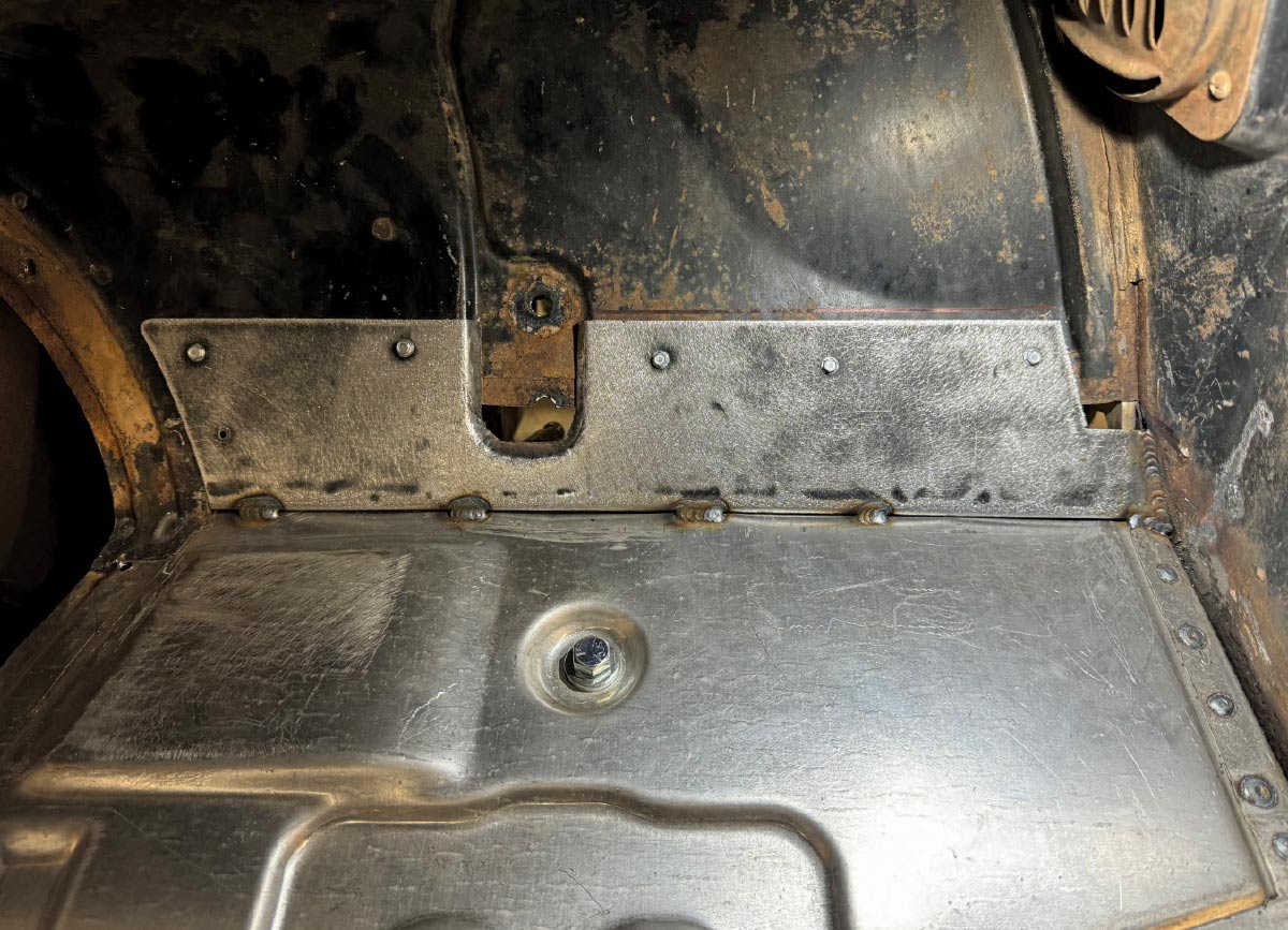 View of small steel patch panels welded in to bridge gaps between the new floor pans and the original firewall.