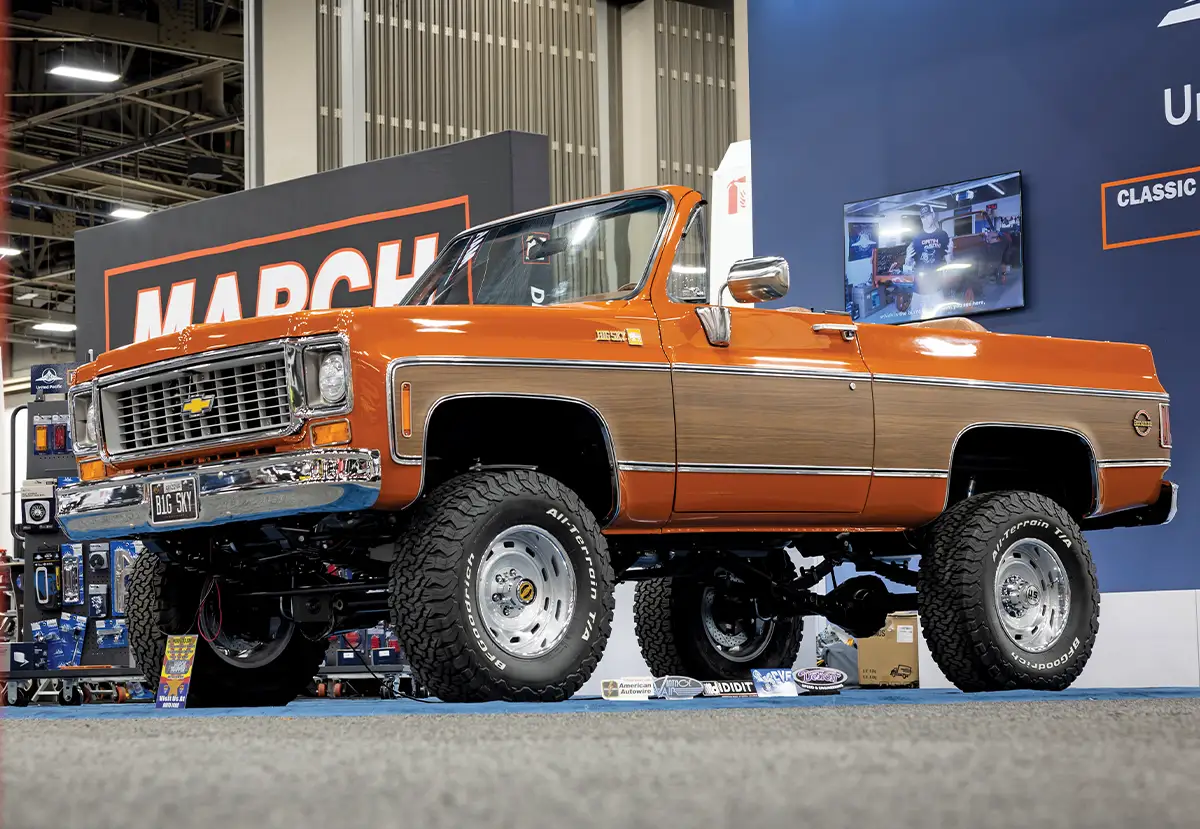 A professional indoor photograph of a show-quality classic Chevy Blazer 4x4 with no top, chrome bumpers, and a highly detailed undercarriage in a convention center setting