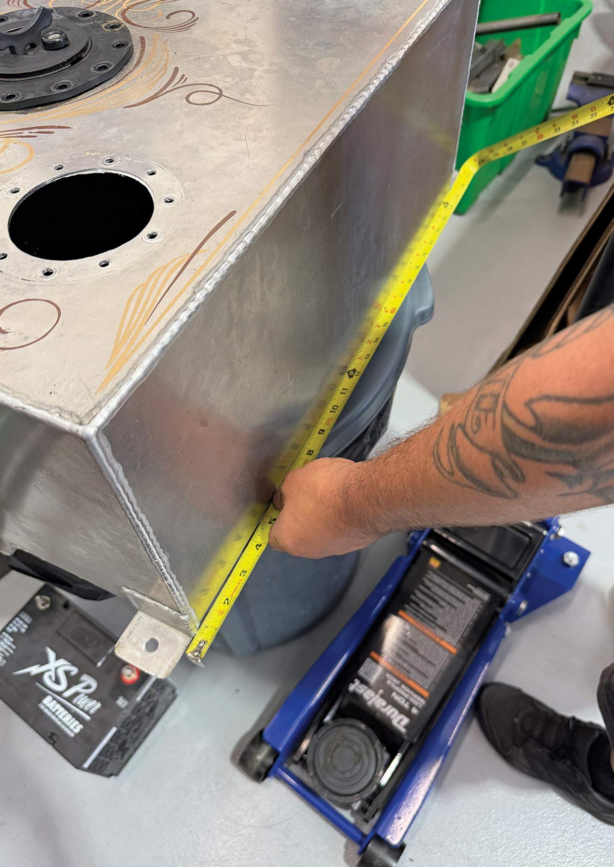 Using a tape measure to verify the 10-inch depth of the fuel tank while on a floor jack.
