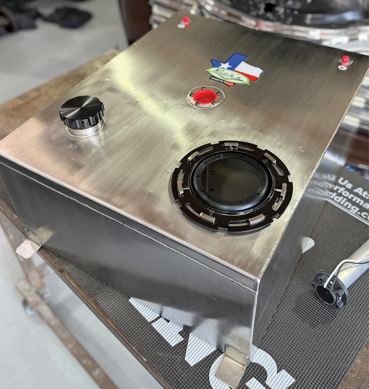 Close-up of Rick’s stainless fuel tank with the "Made in Texas" logo and black fuel filler cap.