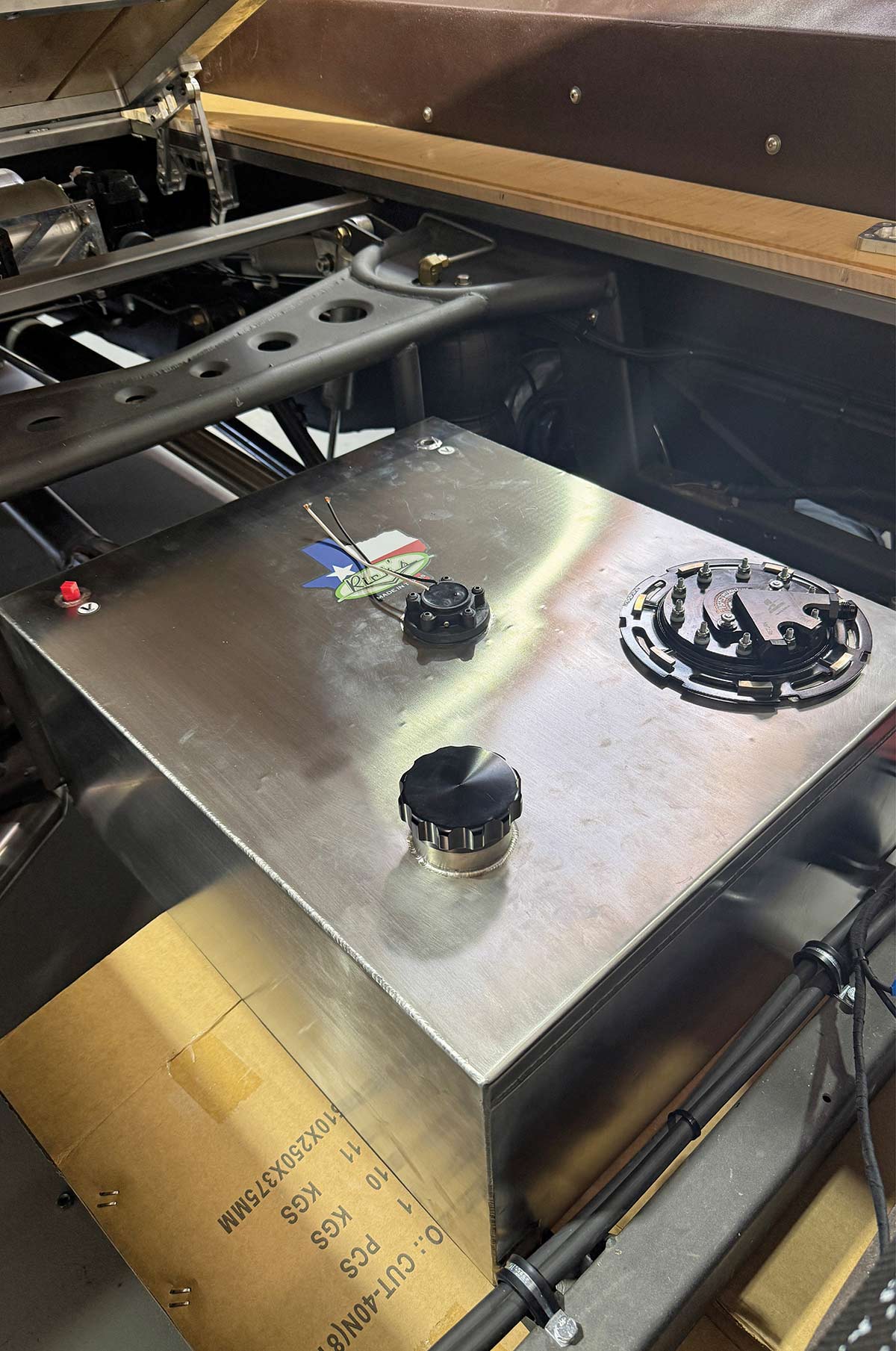 High-angle view of the completed fuel tank installation sitting within the Chevy truck's rear frame rails.