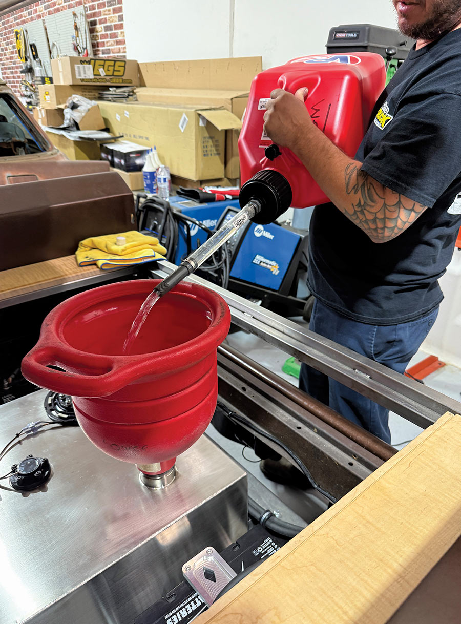 Filling the newly installed Rick’s Tank with fuel using a red VP Racing jug and a large red funnel.