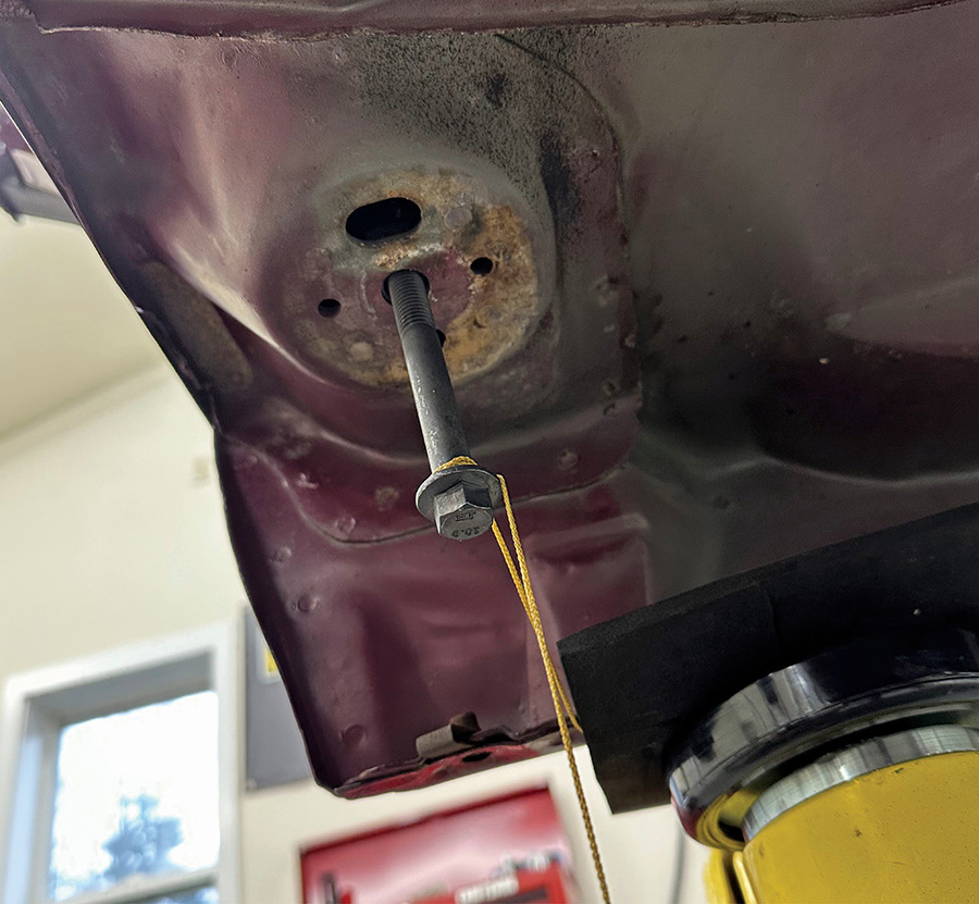 Plumb bob hanging from cab mounting bolt for alignment.
