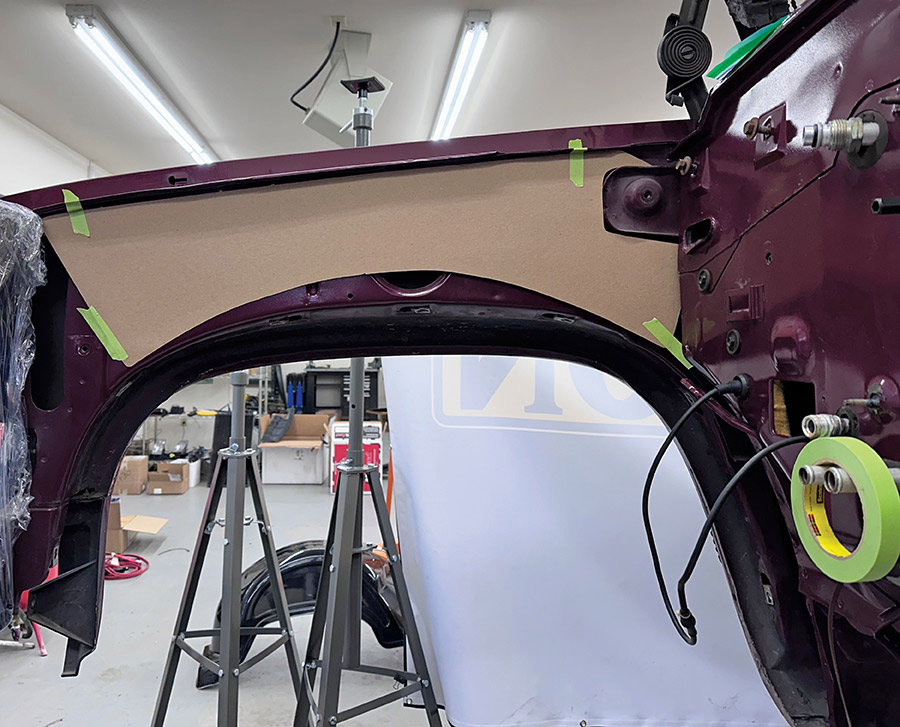 Cardboard template marking the inner fender for modification.
