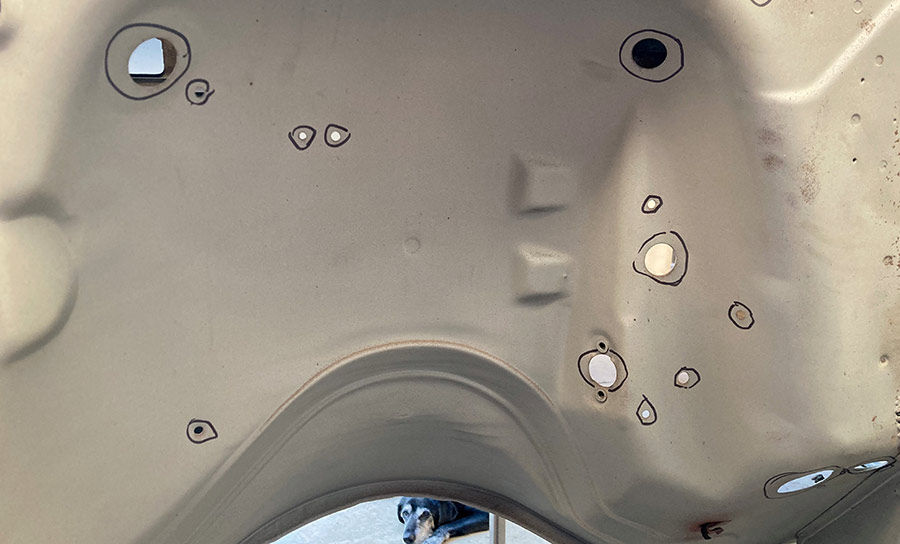Close-up of marked holes and repairs on the firewall