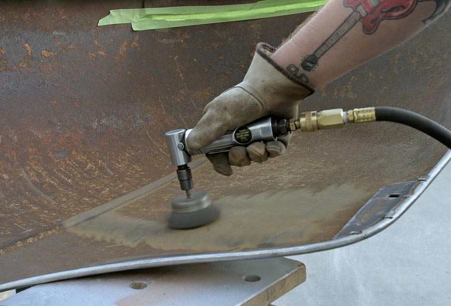 Angle die grinder with wire brush removing loose rust.