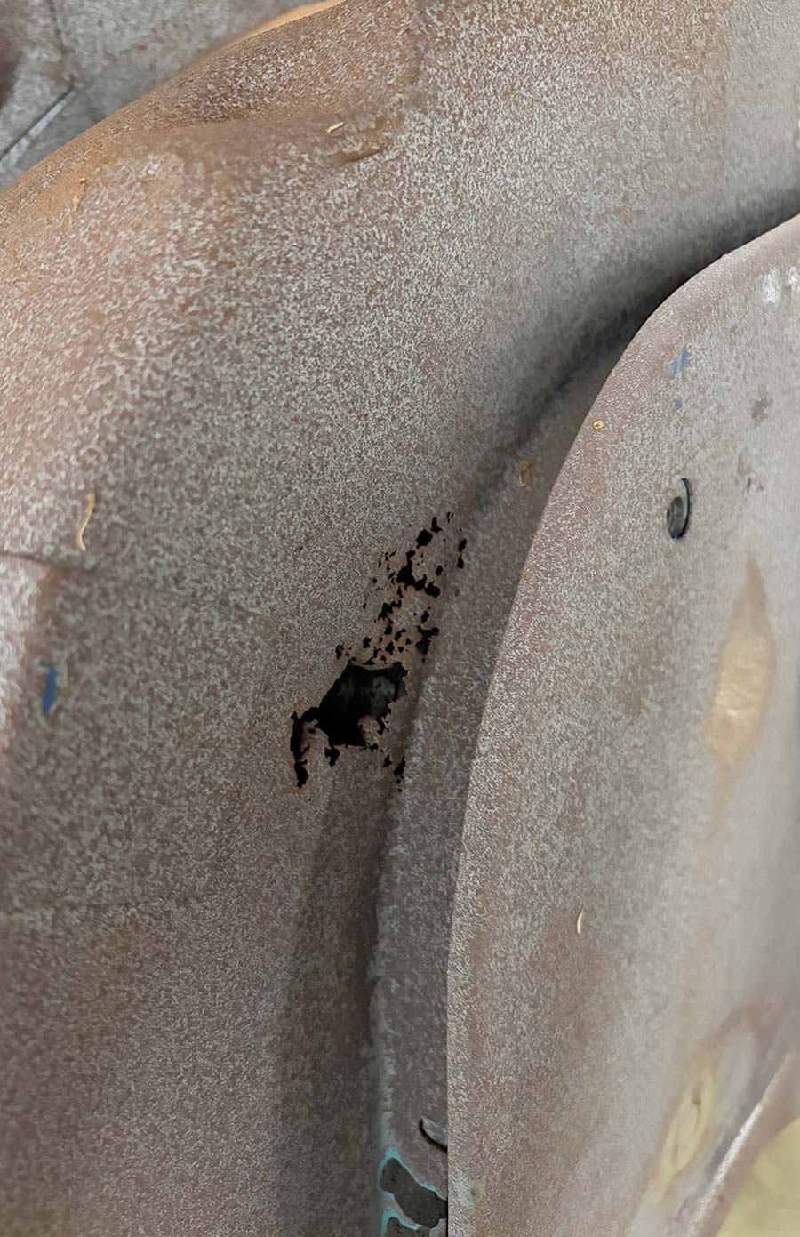 Rusted-through hole in a sheet metal panel.